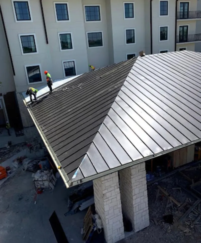 Crew installing standing seam metal roof panels on a commercial project in Manassas